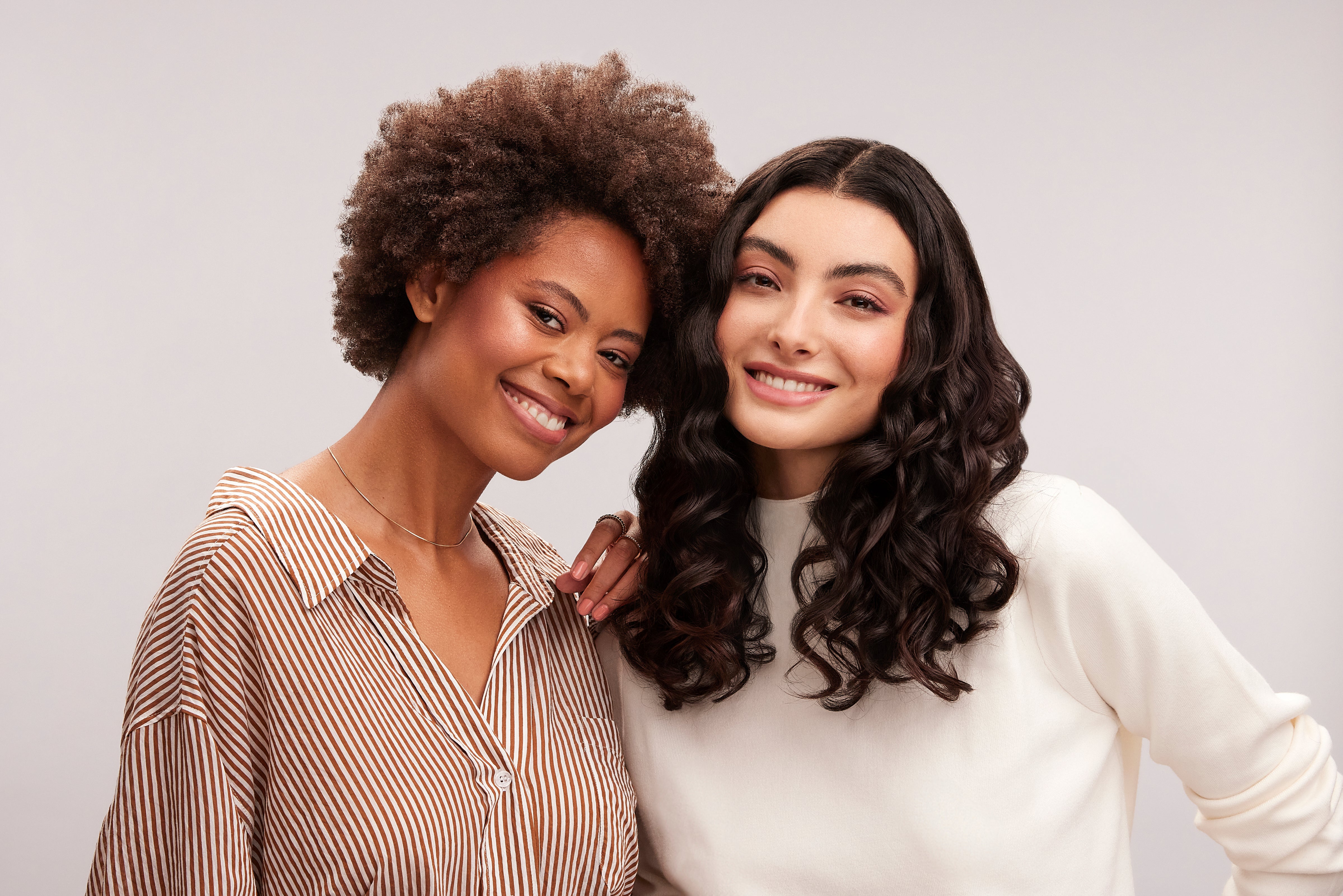 Model with coily hair and model with wavy hair