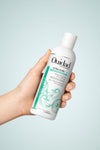 Hand holding bottle of VitalCurl®+ Tress Effects® Styling Gel on light blue background